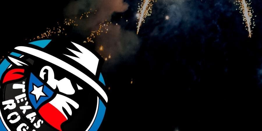 Texas Rogue Fireworks logo with a Texas cowboy wearing a hat and handkerchief in the Texas flag. Click to shop Texas Rogue Fireworks products available at Elite Fireworks. Explosive fireworks backdrop. Logo represents Texas pride in red, blue, and white.